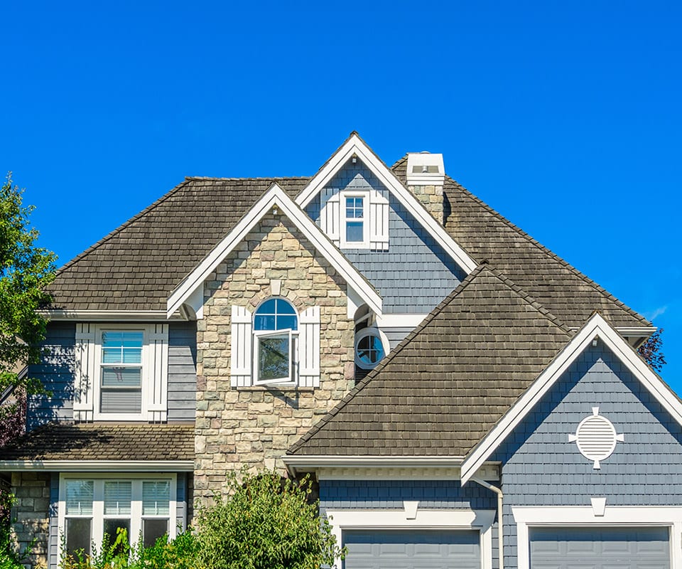 A beautiful home with white shutters, rich storm gray Certainteed shingles, and siding in simulated stone and French Blue. With the right roofing company and remodeler, your home can look amazing inside and out.